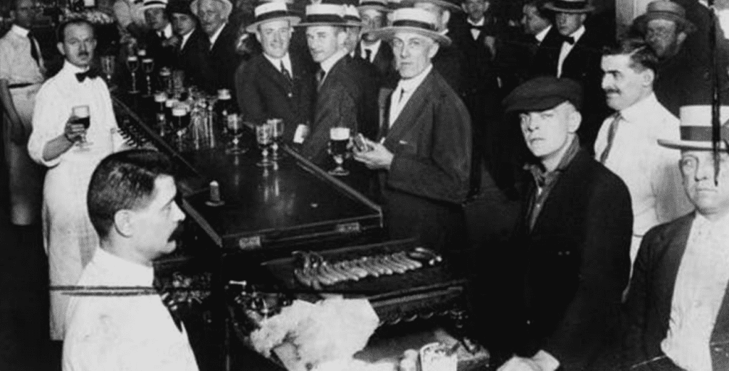 Black and white image of men in a speakeasy bar holding drinks. East Village Prohibition Pub Crawl